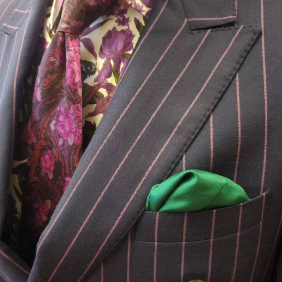 A man in a suit and tie with a green pocket square.